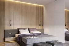 a stylish minimalist bedroom with a light-stained wall, a grey bed and floating nightstands, leather poufs and black wall sconces