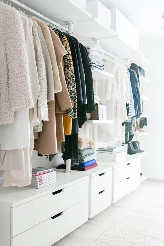 a stylish white minimalist closet with dressers, open shelves and holders for clothes hangers plus white boxes