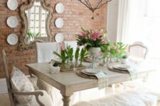 a sweet shabby chic dining room with wooden furniture, pink tulips, a vintage chandelier and a gallery wall with a mirror and plates