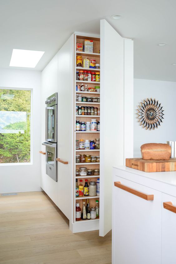 a very narrow and tall storage unit with lots of shelves lets you store a lot of stuff hidden and the kitchen looks sleek