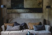 a wabi-sabi interior with a rough wooden wall, a wooden wall art of rough elements and a coarse textile sofa