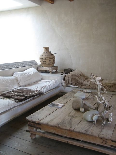A wabi sabi living room with brutal wooden furniture, vases, stones and concrete walls