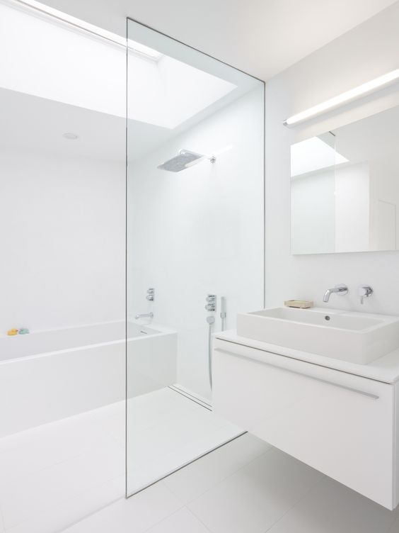 A white minimalist bathroom with a skylight, a white floating vanity, white appliances and built in lights