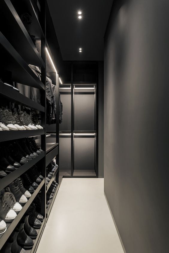 An ultra minimalist black and graphite grey closet with lots of shoe shelves and some drawers plus holders for hangers