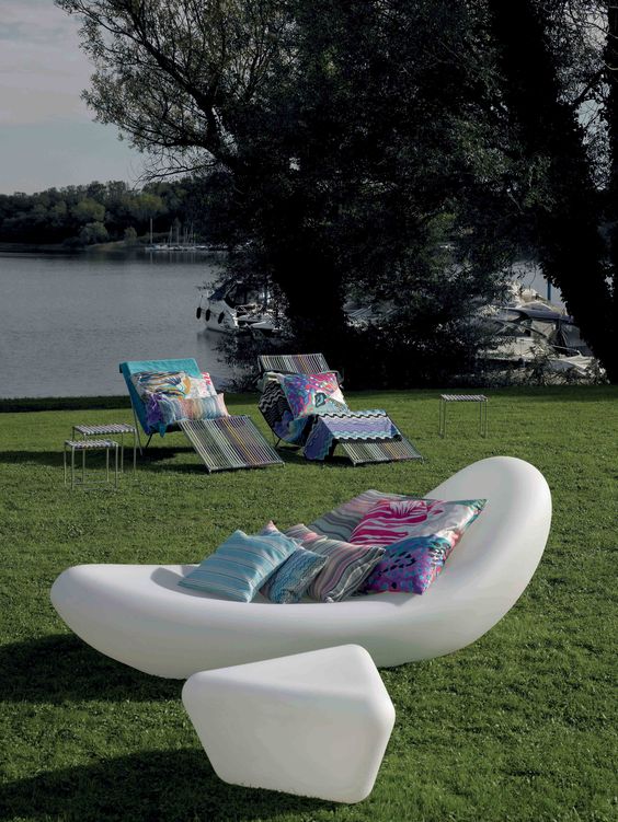 An ultra modern white floating lounger with bright pillows and a matchign geometric side table for a modern space