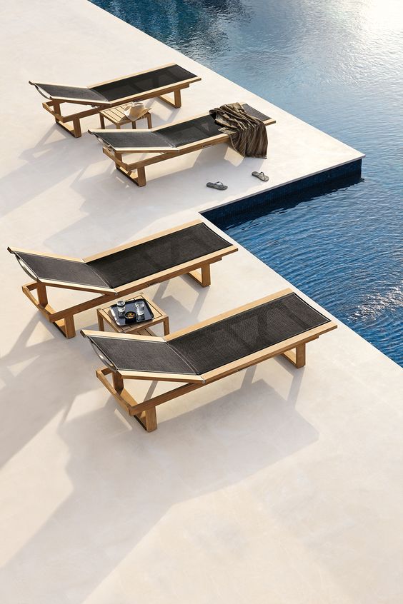 minimalist light-colored wood loungers with black fabric are a nice match for a minimalist outdoor space
