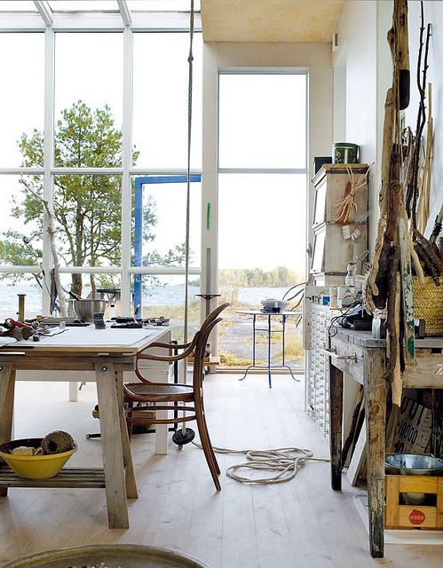 a Scandinavian studio with vintage furniture and accessories, a glazed wall and ceiling and amazing views of a water body