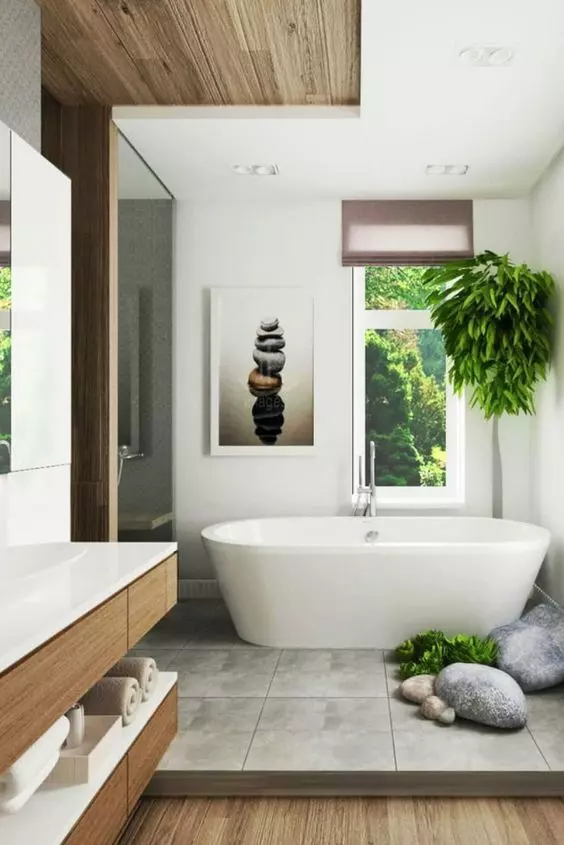 a contemporary home spa with a flaoting vanity, an oval tub, greenery and rocks and an artwork of balancing rocks