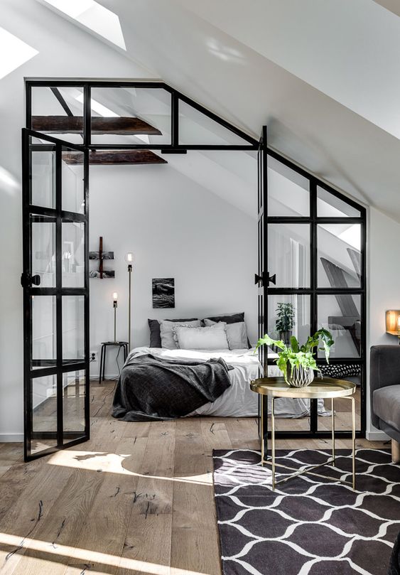 a cozy Nordic bedroom with a bed, nightstands, skylights, table lamps and a glass wall with a door to connect it to the rest of the space