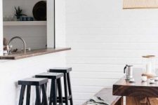 a cozy white pass through space with a narrow windowsill and black stools plus a real dining zone