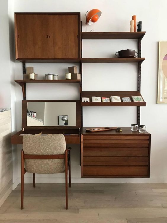 A dark stained storage wall unit with open shelves and cabinets plus a desk with a mirror under it is a cool option for a mid century modern space