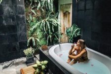 a fully secluded outdoor spa with planted greenery and a living wall, a tub and some tiles plus a wooden mat