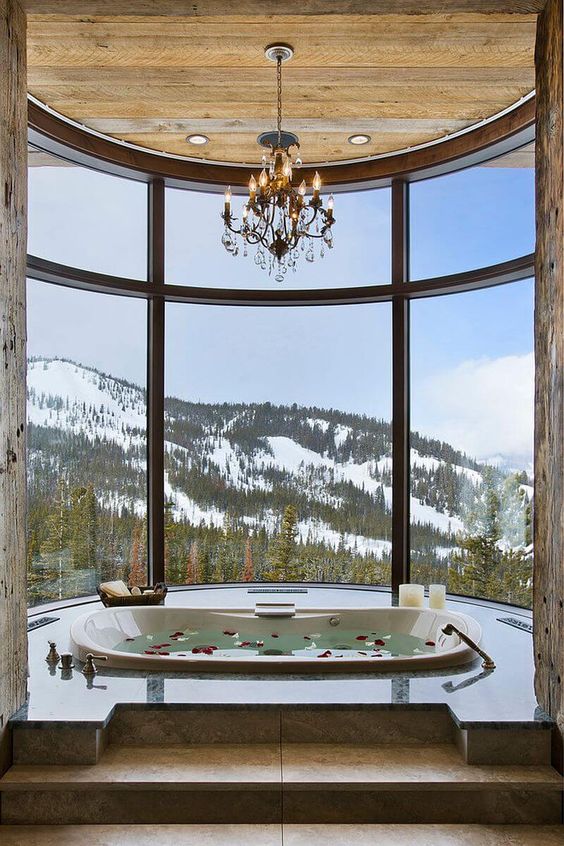 a gorgeous bathroom with a panoramic view, a sunken bathtub, a chandelier, candles is a fantastic space to enjoy your bath time