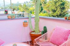 a hot pink terrace with forged furniture, potted cacti and bright pillows is a lovely and feminine space