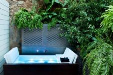 a jacuzzi, lush greenery around it, a crate with towels and some blooms for a welcoming space