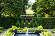 a large cool modern fountain surrounded with bold blooms and greenery is a fantastic idea for a modern outdoor space