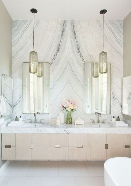 a luxurious white marble accent wall completes the neutral and veyr chic look of this bathroom