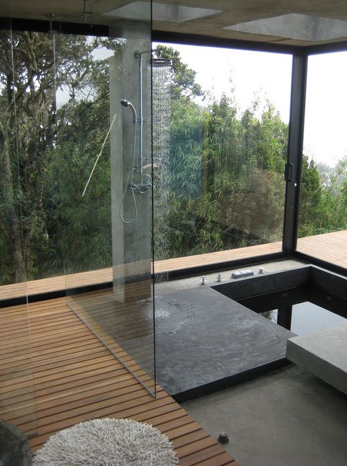 a minimalist bathroom with a wooden deck, a concrete shower space and a sunken bathtub plus a panoramic view