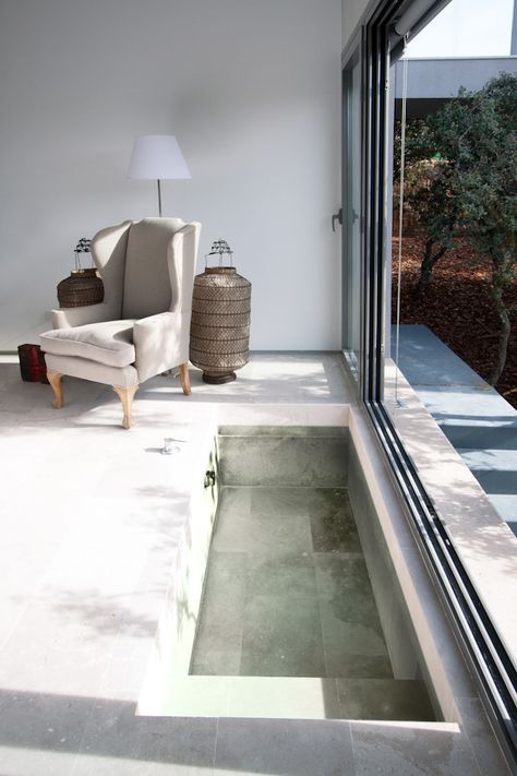 a minimalist sunken bathtub right in the bedroom, with a sliding door to make this space outdoor at once