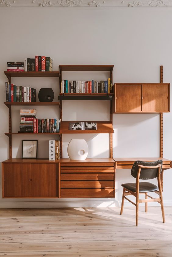 A rich stained modern wall storage unit with open shelves and drawers and cabinets plus a small desk