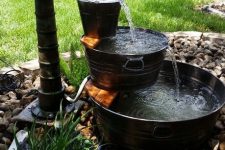 a rustic tiered fountain with galvanized buckets and bathtubs plus pebbles and blooms around is amazing
