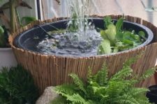 a small and pretty fountain in a bowl with greenery surrounded with a potted plants and with a bamboo cover is a lovely idea for an Asian garden
