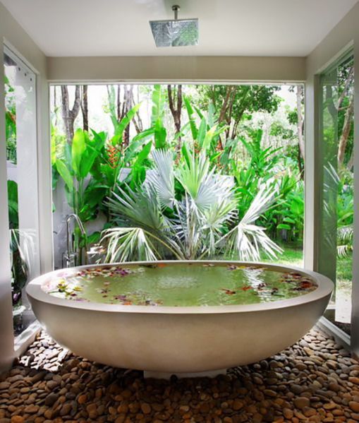 an oval bathtub placed on pebbles feels like a real spa and can be opened up to outdoors any time