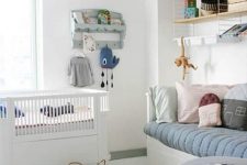 a Nordic kid’s room with a daybed, a crib, a shelving unit and a rack, some pastel decor and bedding
