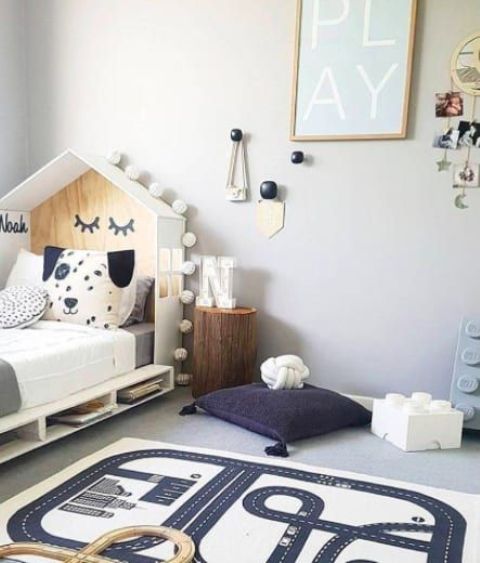 a Nordic kid's room with a house-shaped bed with storage, a stump, pillows, wall decor and a map rug for playing