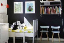 a Nordic kid’s room with vintage white furniture, a wall shelf, a black statement wall, colorful books and buntings