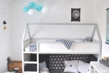 a Scandi kids’ room with a bunk bed, printed bedding, a striped rug, a white table and chair, a white storage unit