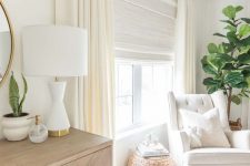a beautiful creamy space with a neutral Roman shade and creamy curtains to block out the sun when the baby’s sleeping