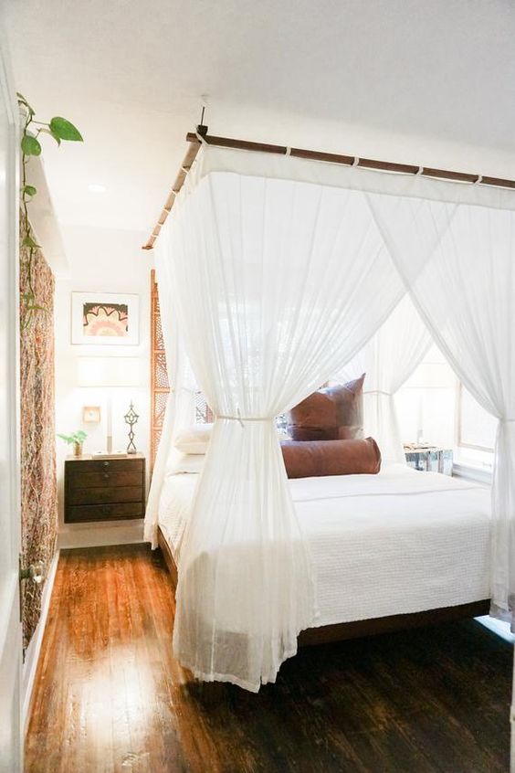 a bed with a bamboo frame and a mosquito net canopy that keeps bugs away and add colonial style to the bedroom
