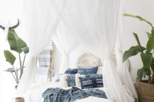 a boho tropical bedroom with mosquito net curtains hanging on bamboo frames looks very welcoming