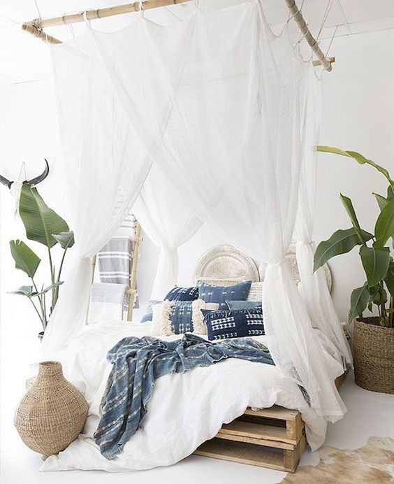 a boho tropical bedroom with mosquito net curtains hanging on bamboo frames looks very welcoming