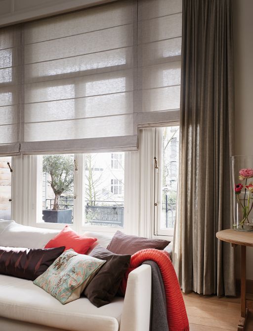 a chic contemporary living room with tan Roman shades and brown curtains that provide light blocking and privacy when needed