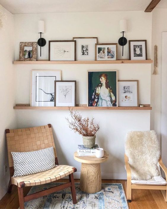 a chic reading nook with a couple of stylish chairs, wodoen ledges for displaying art and photos, a wooden table and a printed rug