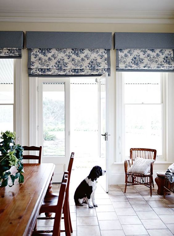 a classic dining room with windows and doors styled with blue floral print Roman shades is a cool bold space