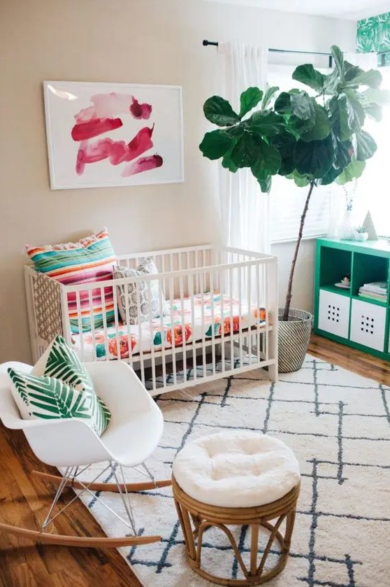 A colorful tropical inspried small nursery with floral, palm prints, potted greenery and artworks