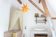 a dreamy attic nursery with wooden beams, vintage furniture, a canopy, stars and baskets plus a cute rug