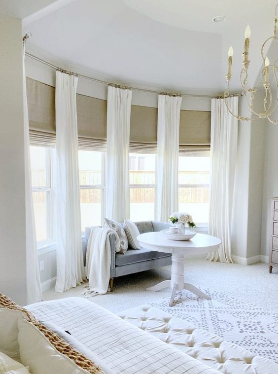 a gorgeous bay window with burlap Roman shades and creamy curtains is a lovely idea for a refined neutral interior like this one