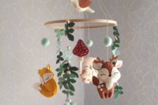 a gorgeous woodland felt mobile with deer, foxes, an owl, leaves, pompoms and mushrooms plus a bird on top for a woodland nursery