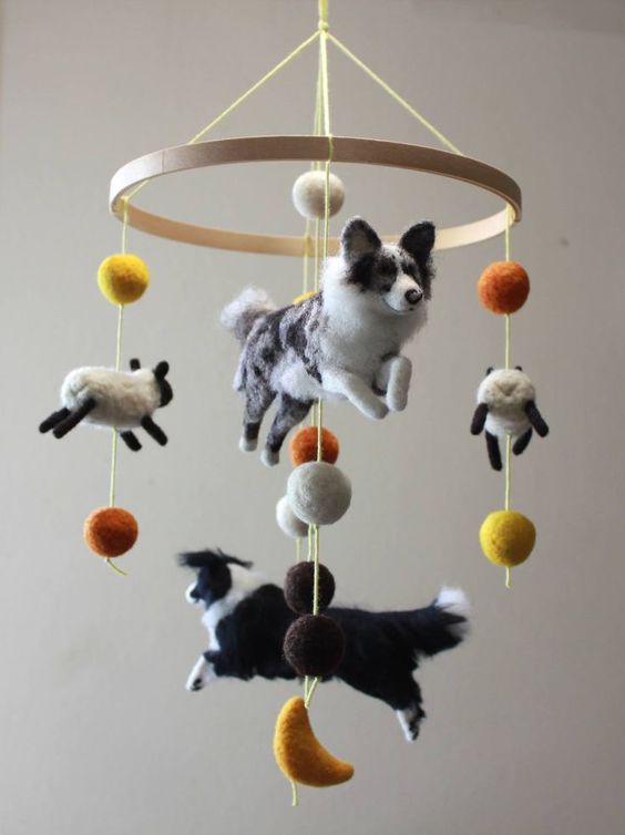 a jaw-dropping farm-themed mobile with dogs and sheep plus colorful pompoms is a very creative and fun solution