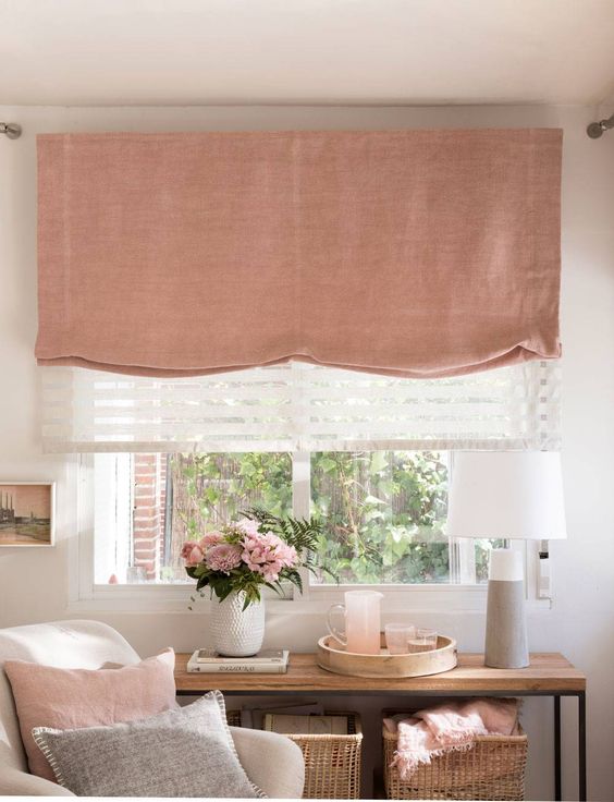 a lovely feminine space with a pink Roman shade that echoes with other pink decor in the room and makes it cooler