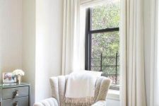 a lovely reading nook by the window styled with a printed Roman shade and creamy curtains is very lovely