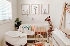 a mid-century modern meets boho nursery with layered rugs, a crib with bright bedding, an additional crib, a white dresser and a gallery wall
