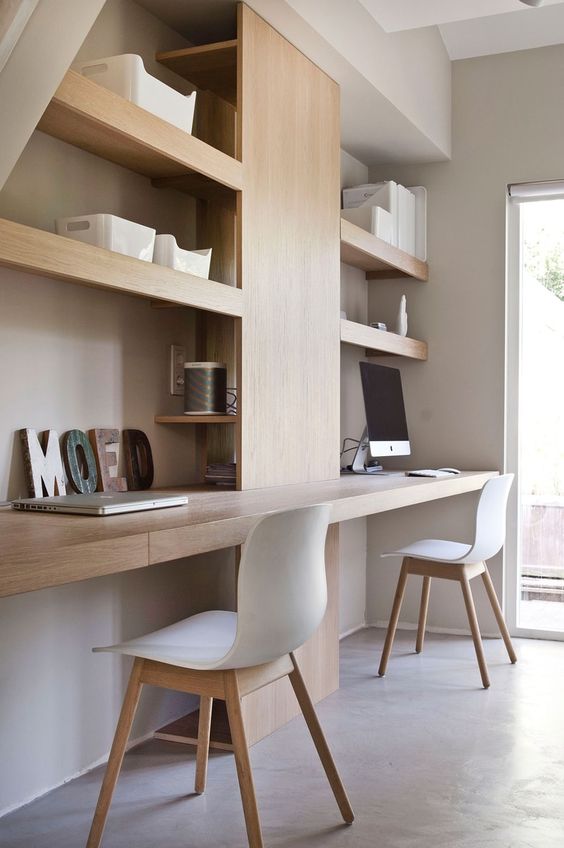 A minimalist shared home office with built in shelves and desks, white chairs and a window for more natural light and a view