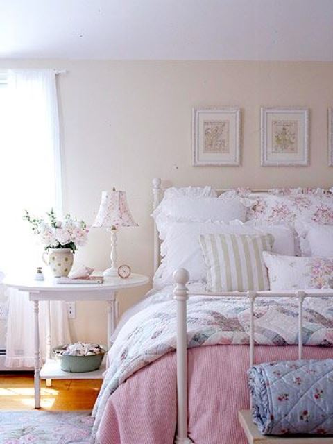 a neutral and pastel bedroom in shabby chic style, with a white forged bed, white wooden furniture, floral bedding and a gallery wall