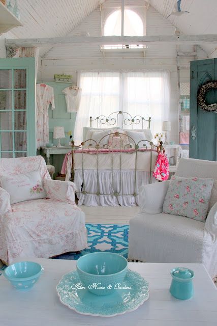 a neutral and pastel shabby chic bedroom with a forged bed, a minty door, floral bedding and white furniture