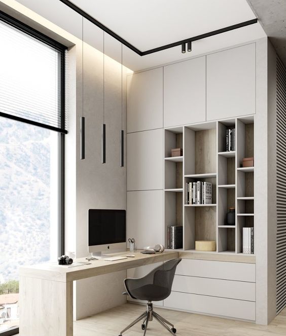 a neutral minimalist home office with light grey storage units and open storage compartments, a built-in desk and a black chair is chic